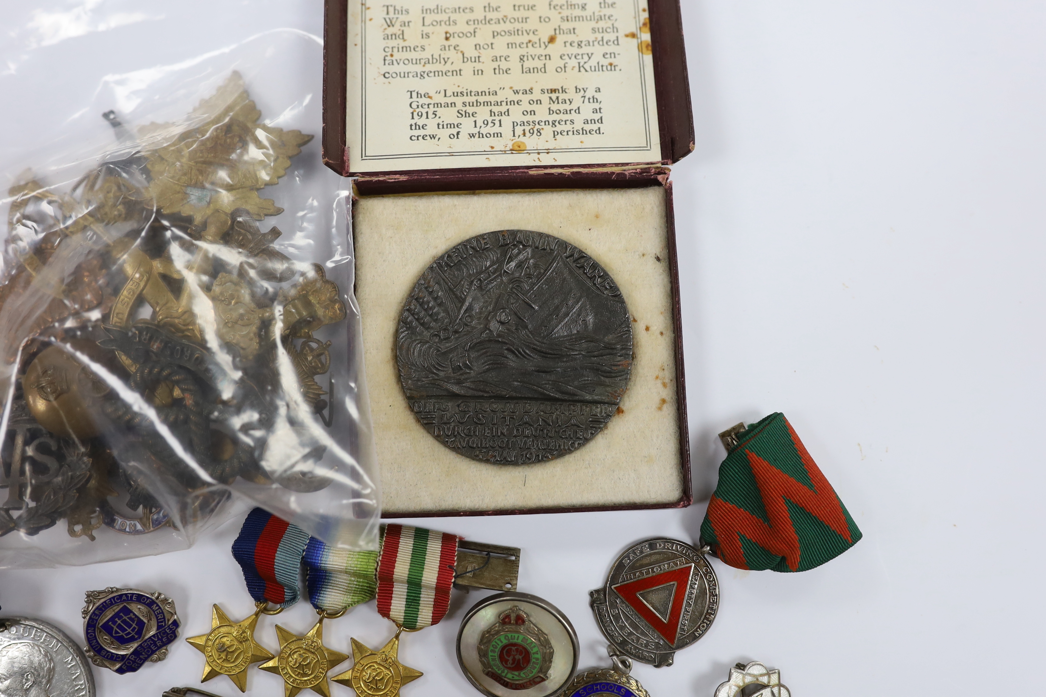 A collection of medals, cap badges, commemorative coins etc. including; a cased RMS Lusitania medal, Royal Artillery sweetheart brooches, a miniature WWII medal group of three stars; the 1939-45 Star, the Atlantic Star a